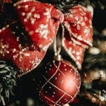 Close-up of a festive red Christmas ornament with gold accents on a decorated tree.